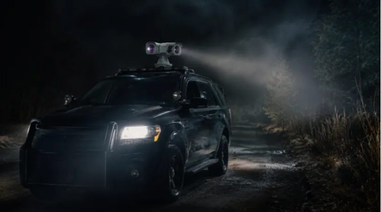 Rugged police vehicle with roof-mounted thermal PTZ camera scouting a dark roadside at night